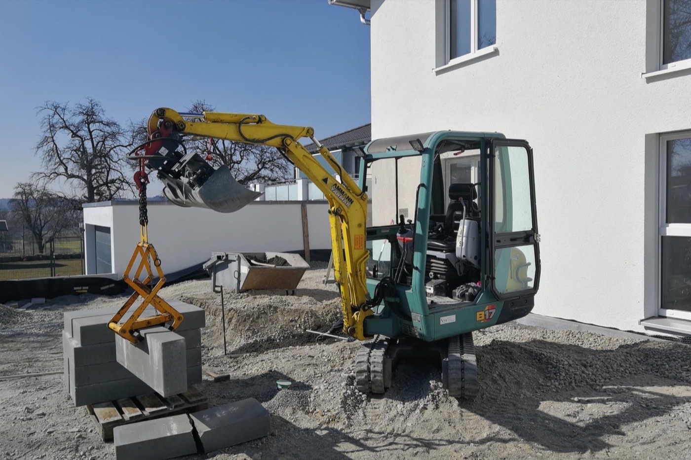 Bagger setzt mit der Steinzange eine große Platte an einer Hauswand